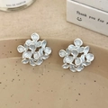 Macro view of French vintage floral stud earrings with blue enamel petals on a ceramic dish - Blue