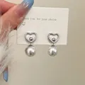 Dettaglio di orecchini a cuore in argento con cristalli e una grande perla bianca pendente - Orecchini a lobo a cuore argentati