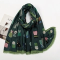 Detail of dark green scarf featuring colorful cartoon cat patterns and fringe edges - Dark Green