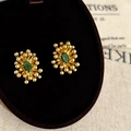 Elegant gold-plated floral earrings with emerald zircon center on jewelry box - Gold Green Zirconia