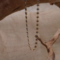 Detailed shot of a gold flower necklace with blue beads draped on a natural branch - Blue Flower (B-41)