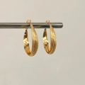 Dettaglio di orecchini a cerchio dorati con texture intrecciate lucide e satinate - Orecchini a Cerchio Dorati 4cm