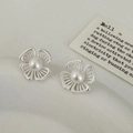 Detalle de pendientes de flores huecas plateadas con perlas en fondo vintage - Pendientes de botón de flor plateada