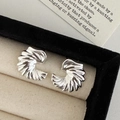 Détail de boucles d'oreilles ailées en argent avec texture plissée sur plateau velours - Argenté