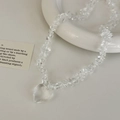 Close-up of heart pendant and transparent white crystal stone necklace on white surface - Transparent Crystal Chip Heart Necklace