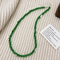 Elegante groene chalcedoon kralenketting met zilveren strikjes op zachte gebreide stof - Groene Chalcedoon Ketting