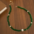 Dettaglio della collana in calcedonio verde smeraldo e perle su superficie in legno scuro - Verde Doppio Strato