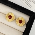 Detail of vintage gold ripple earrings with dark red stones on a velvet tray - Red Enamel Stud Earrings