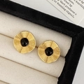 Macro shot of gold circular earrings with black center in a cream velvet jewelry box - Black Oil Drop Stud Earrings