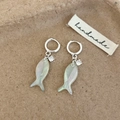 Silver fish earrings with iridescent shell texture and clear zircon on a warm background - Blue Fish Earrings