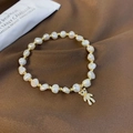 Detailed close-up of a freshwater pearl bracelet with a sparkling gold bear charm pendant - Bear Style
