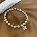 Detail of freshwater pearl bracelet with zircon flower charm on brown silk fabric - Flower Style