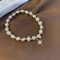 Close-up of freshwater pearl bracelet with a sparkling gold star pendant on silk - Eight-pointed Star Style