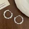 Macro detail of silver organic textured hoop earrings with liquid metal finish on wood - Silver