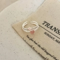 Dettaglio anello con gemma cuore rosa e accenti floreali su fondo in tessuto vintage - Cuore di Zircone Argento
