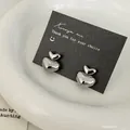 Minimalist double heart silver studs displayed on black card in a white ceramic dish - Silver Heart Pendant Earrings / Silver