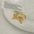 Gouden bow ring met witte zirkoon op een minimalistisch keramisch bord geplaatst - Gouden Kralen Strik Open Ring (C-11)