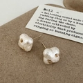 Detail of irregular white pearl studs with gold accents on a textured brown background - Clover Flower Cotton Pearl Stud Earrings