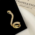 Detail of gold snake ear cuff with white cubic zirconia and a green gemstone eye - Gold