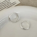 Detail van zilveren oorringen met een handgemaakte gehamerde textuur en een golfdesign - Gehamerd Model / Zilver