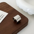 Primo piano di un ear cuff largo in argento lucido con design minimalista a forma di C - Argento