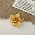 Macro detail of golden flower ring with textured petals and a sparkling central zircon - Gold Flower Ring