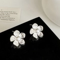 Dettaglio macro di orecchini a fiore in argento con perla su una superficie riflettente - Argento