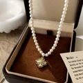 Dettaglio della collana di perle con ciondolo a quadrifoglio dorato in scatola - Collana a Quadrifoglio di Perle Dorate