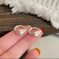 Orecchini a cerchio minimalisti a forma di foglia d'argento mostrati sul dito per la scala - Argento Spazzolato