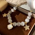 Detail of cat eye stone bead bracelet with star charms and shell pendant in jewelry box - Gold Star Cat Eye Stone Shell Bracelet