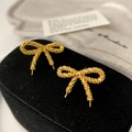 Detail of golden bow earrings featuring a textured crushed silver finish on black velvet - Gold Bowknot Stud Earrings