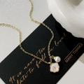 Elegant gold necklace with a white round pearl and iridescent shell pendant on black card - Gold Shell & Lustrous Pearl Necklace