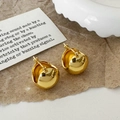 Nahaufnahme von glänzenden Goldkugel-Ohrringen auf elegantem braunem Strukturpapier - Goldene Kugelohrringe / Gold