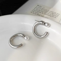 Close-up of minimalist C-shaped silver earrings with white pearls on a white plate - Silver Pearl Stud Earrings