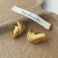 Dettaglio ravvicinato di orecchini a spirale dorati su un vassoio di carta marrone - Oro