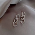 Detalle macro de pendientes de cadena de plata sobre un fondo de suave tela de raso gris - Plateado