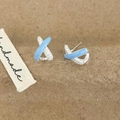 Macro detail of X-shaped cross earrings with light blue enamel and sparkling zircon - Blue