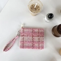 Roze tweed make-uptasje met parel rits en polsbandje op een witte achtergrond display - Roze