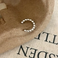 Macro-opname van een zilveren kralen ear cuff in C-vorm op een getextureerde stof - Zilver