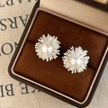 Dettaglio macro di orecchini floreali in argento con perla bianca e piccoli cristalli - Argento