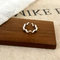 Close-up of silver wavy geometric ear cuff on a wooden block with textured background - Silver