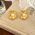 Detalle de pendientes de flor vintage dorados con perla sobre un fondo de tela rústica - Dorado