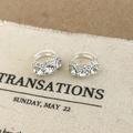 Primer plano detallado de pendientes de aro de circonita sobre fondo de tela clara - Color Plata Pendientes de Diamantes de Imitación Blancos