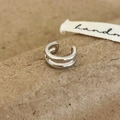 Dettaglio del doppio polsino per orecchio in argento minimalista su carta kraft marrone - Argento