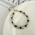 Dettaglio del bracciale regolabile con perle grigie e nere su vassoio di ceramica - Bracciale con Sfera Shamballa Nera