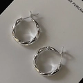 Primo piano di orecchini a cerchio intrecciati argento dal design minimalista elegante - Argento