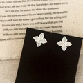 Close-up of silver clover stud earrings with sparkling cubic zirconia on black card - Silver