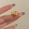 Detail of a minimalist gold intertwined knot ring with an adjustable open band design - Open Knot / Gold
