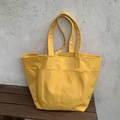 Borsa tote in nylon giallo brillante con tasche multiple e spallacci su panca di legno - Giallo