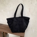 Grande borsa tote in nylon nero con tre tasche anteriori su una panca in legno rustico - Nero